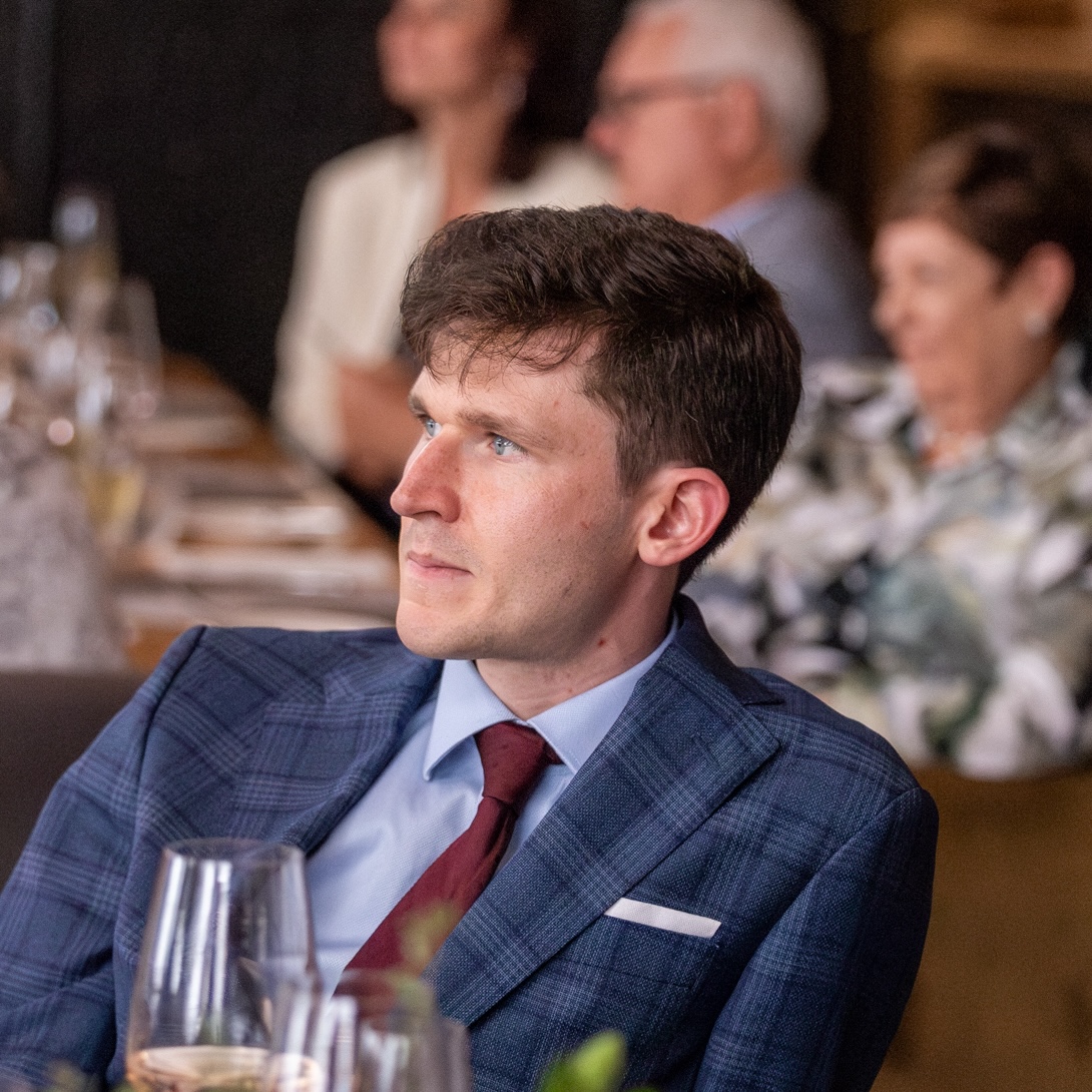 Photo of Alexander Krentsel sitting and looking off to the left pensively.